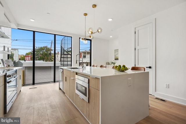 kitchen with stainless steel appliances, visible vents, a sink, modern cabinets, and light wood-type flooring