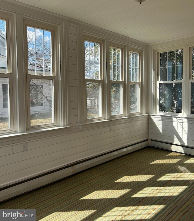 unfurnished sunroom featuring a baseboard heating unit and a healthy amount of sunlight