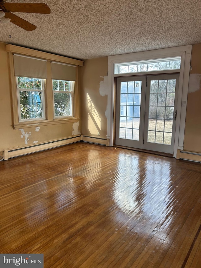 interior space featuring hardwood / wood-style flooring, a baseboard radiator, and a textured ceiling