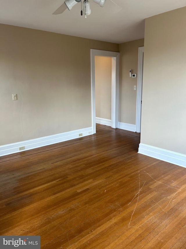 empty room featuring a ceiling fan, baseboards, and wood finished floors