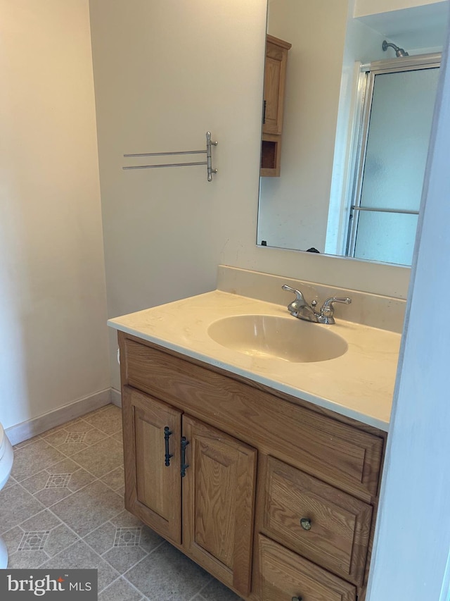 bathroom featuring toilet, vanity, baseboards, a shower, and tile patterned floors