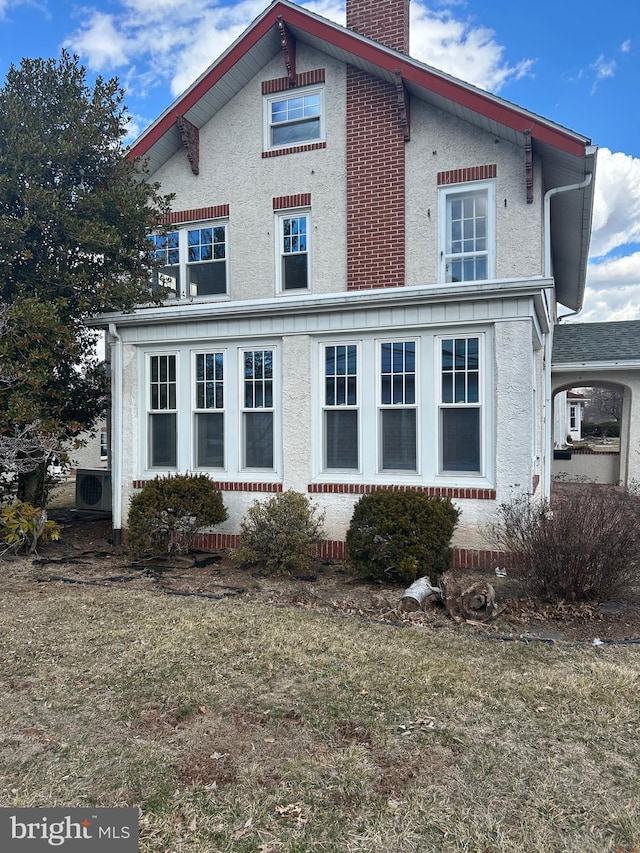 rear view of house featuring ac unit, a chimney, and stucco siding