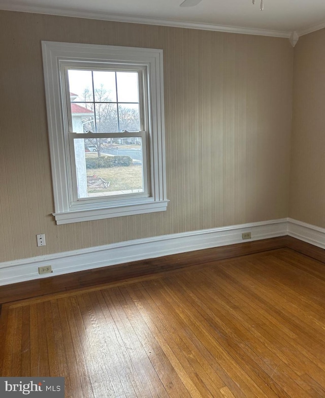 spare room with ornamental molding, wood-type flooring, and baseboards