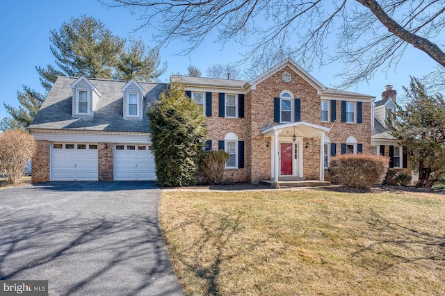 view of front of property with a garage, brick siding, driveway, and a front lawn