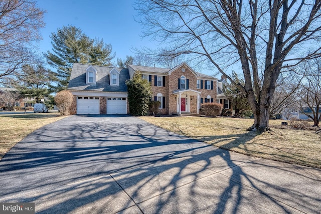 view of front of house featuring a garage, brick siding, aphalt driveway, and a front yard