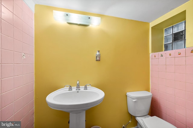 bathroom with toilet and tile walls