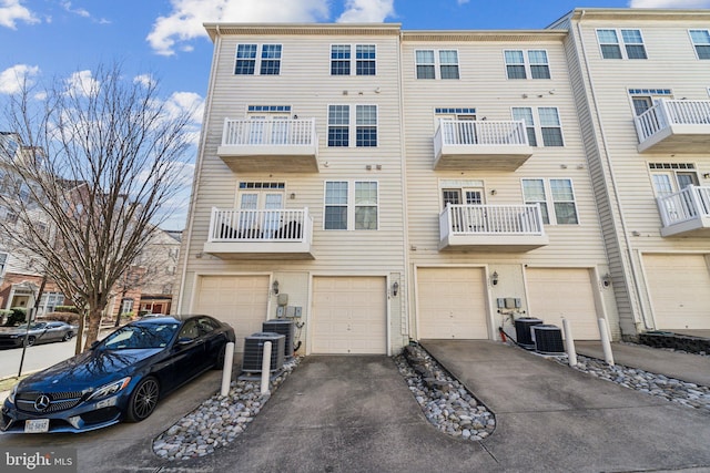 exterior space with an attached garage, cooling unit, and driveway