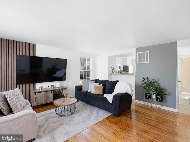 living room featuring wood finished floors, visible vents, and baseboards