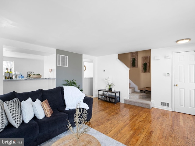 living area featuring visible vents, baseboards, wood finished floors, and stairs