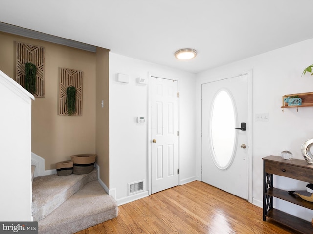 foyer with baseboards, visible vents, and light wood-type flooring