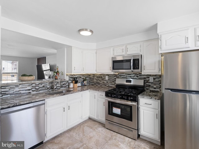 kitchen featuring a sink, stainless steel appliances, dark stone counters, white cabinets, and decorative backsplash