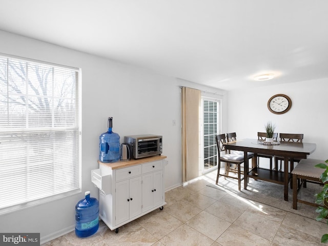 dining space featuring light tile patterned floors, baseboards, and a toaster