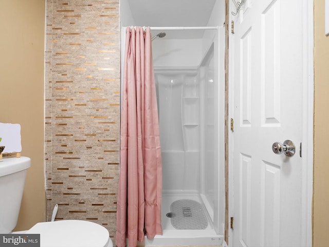 full bathroom featuring a shower stall and toilet