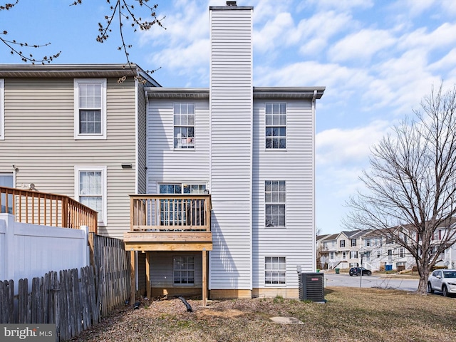 rear view of house featuring central AC, a chimney, and fence