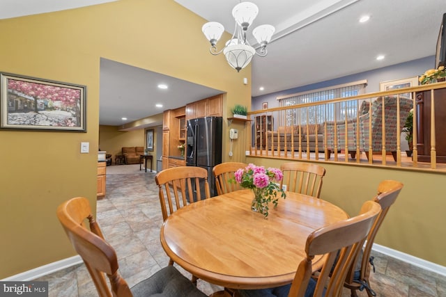 dining space with a chandelier, stone finish floor, and baseboards