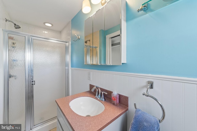 bathroom featuring wainscoting, a shower stall, and vanity