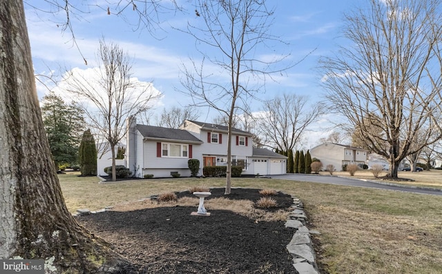 split level home with a garage, aphalt driveway, a front lawn, and a chimney