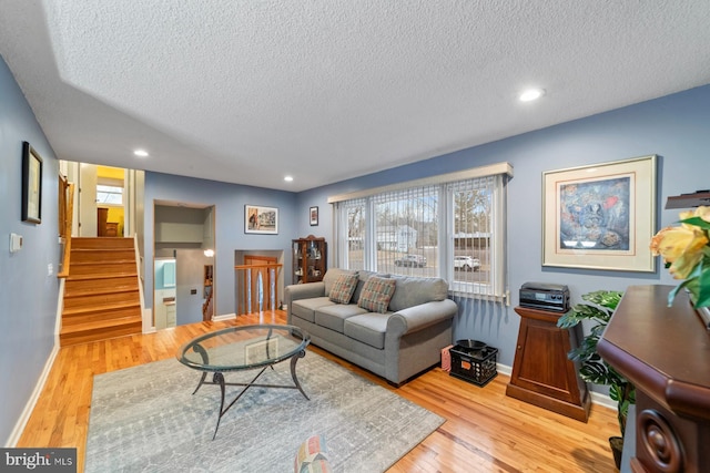 living area featuring recessed lighting, light wood-style flooring, baseboards, and stairs