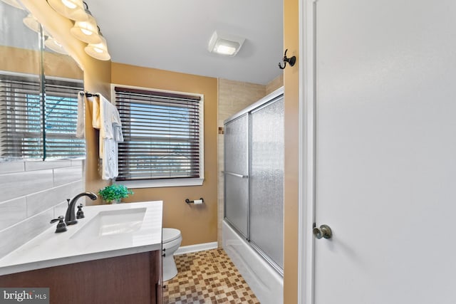 bathroom with baseboards, toilet, enclosed tub / shower combo, tile patterned floors, and vanity