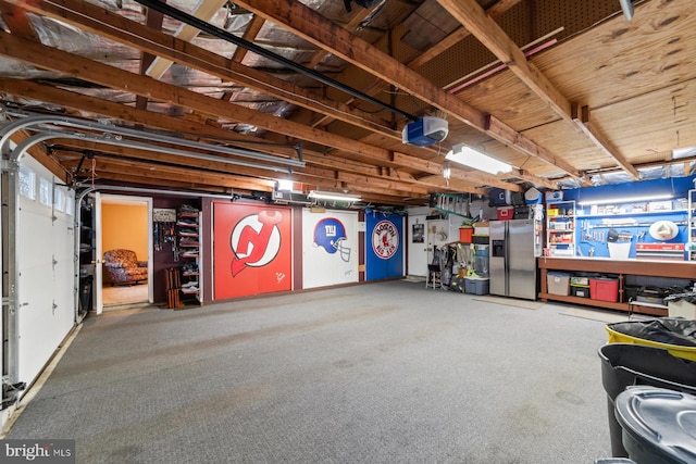 garage featuring a garage door opener and stainless steel refrigerator with ice dispenser