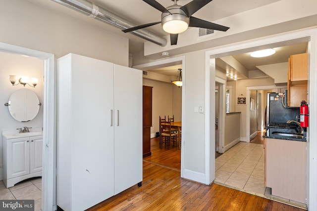 kitchen featuring dark countertops, light wood-style floors, visible vents, and a sink