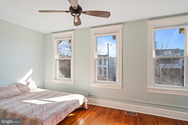 bedroom with baseboards, visible vents, ceiling fan, and wood finished floors