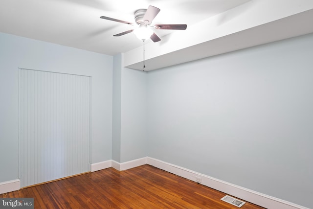 spare room with a ceiling fan, visible vents, baseboards, and wood finished floors