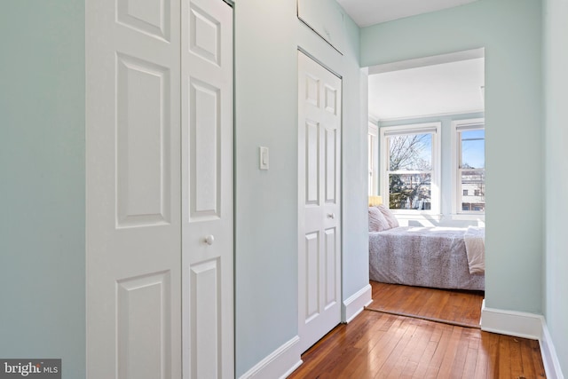 corridor featuring wood-type flooring and baseboards