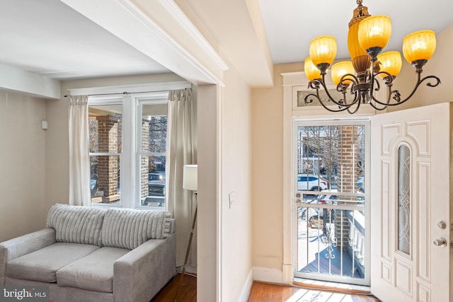 entryway with an inviting chandelier, wood finished floors, and baseboards