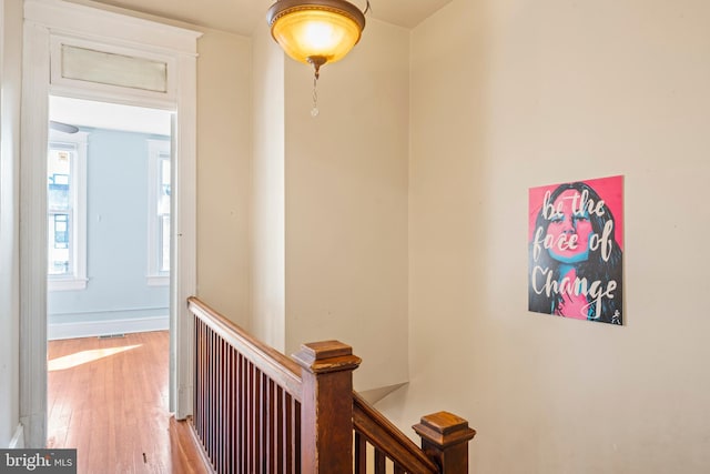 hall featuring baseboards, an upstairs landing, and wood finished floors