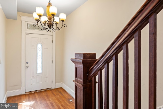 foyer with stairs, baseboards, light wood finished floors, and an inviting chandelier