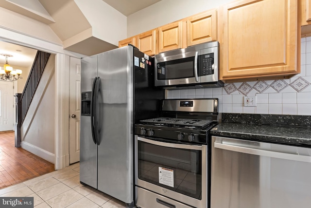 kitchen featuring light tile patterned floors, stainless steel appliances, decorative backsplash, light brown cabinetry, and a chandelier