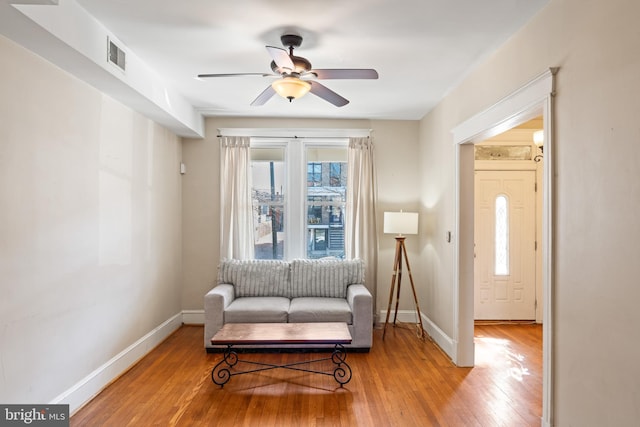 sitting room with light wood finished floors, a ceiling fan, visible vents, and baseboards