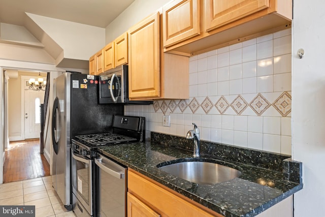 kitchen featuring a notable chandelier, backsplash, light brown cabinetry, appliances with stainless steel finishes, and a sink