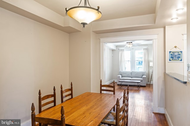 dining space with dark wood-style flooring, a ceiling fan, and baseboards