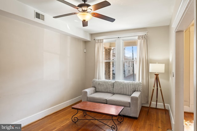 living area featuring ceiling fan, wood finished floors, visible vents, and baseboards