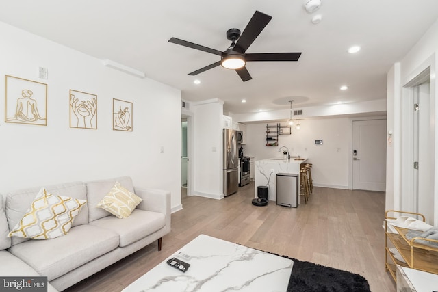 living area with recessed lighting, visible vents, light wood-style floors, a ceiling fan, and baseboards