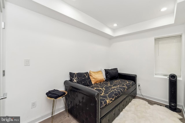 living area featuring recessed lighting, a tray ceiling, baseboards, and wood finished floors