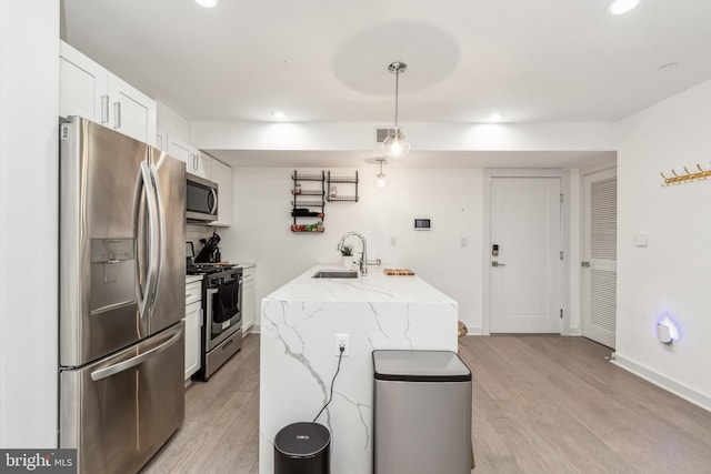 kitchen with a sink, visible vents, white cabinets, appliances with stainless steel finishes, and light wood finished floors