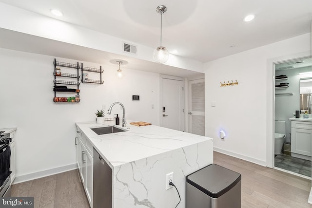 kitchen with baseboards, visible vents, light wood-style flooring, a peninsula, and a sink