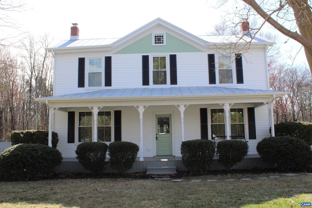 view of front of home featuring a standing seam roof, metal roof, a porch, and a chimney