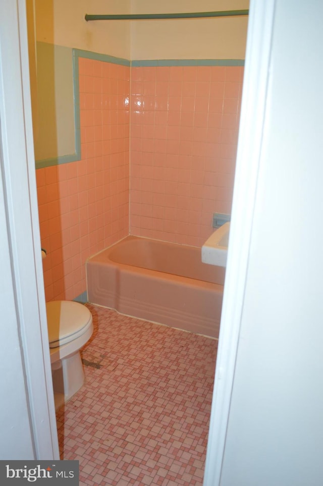 bathroom featuring toilet and tile walls