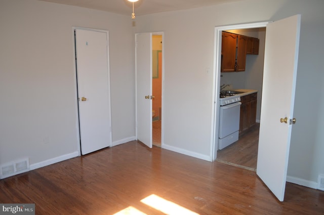 unfurnished bedroom with wood finished floors, visible vents, and baseboards