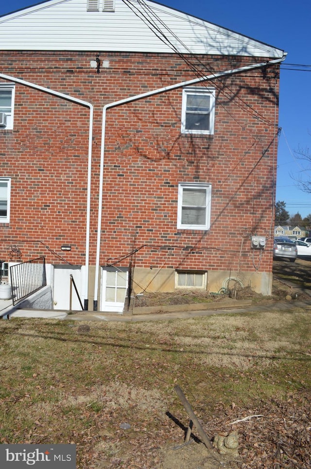 view of property exterior with brick siding and a lawn