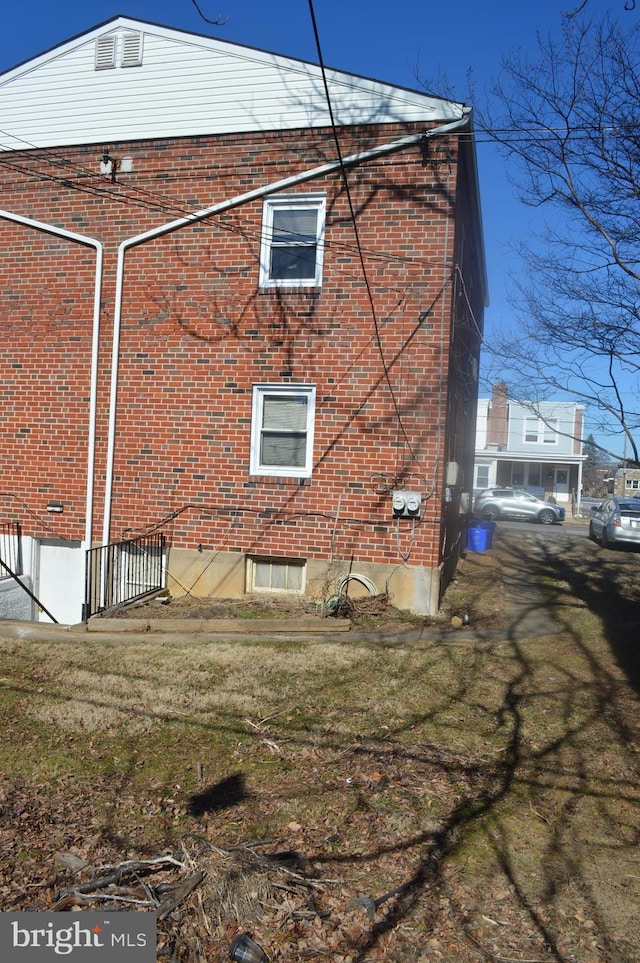 view of side of property featuring brick siding and a lawn