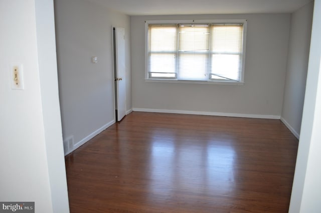 unfurnished room featuring wood finished floors, visible vents, and baseboards