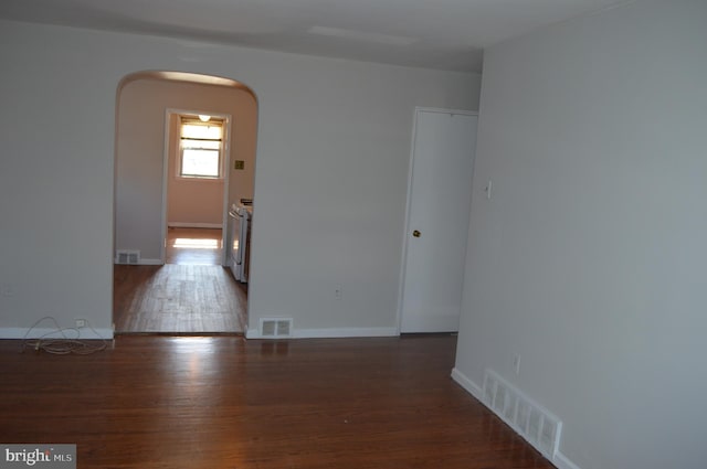 unfurnished room featuring visible vents, arched walkways, and wood finished floors