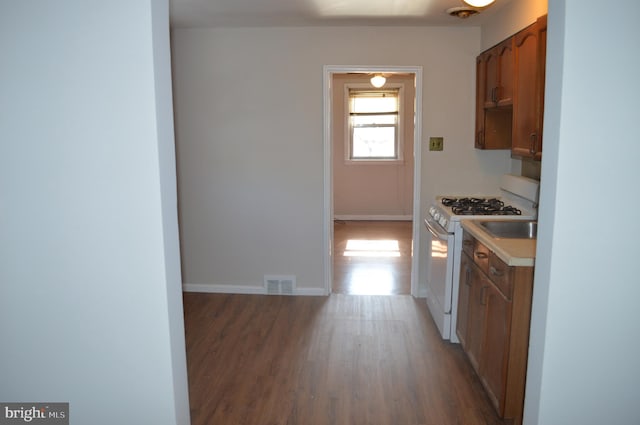 kitchen with wood finished floors, visible vents, baseboards, light countertops, and white gas range