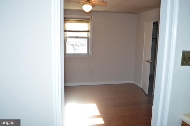 empty room with ceiling fan, baseboards, and wood finished floors