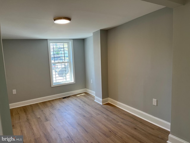 empty room featuring visible vents, baseboards, and wood finished floors